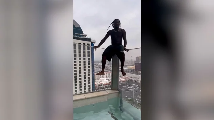 Rapper Offset casually hangs off balcony of a skyscraper leaving Cardi B screaming